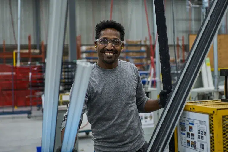 A person smiles at the camera in a warehouse during a company culture video in Calgary.