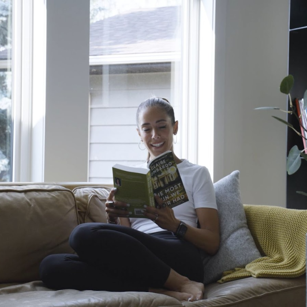 A person sits on a couch and reads a book during a testimonial video in Calgary