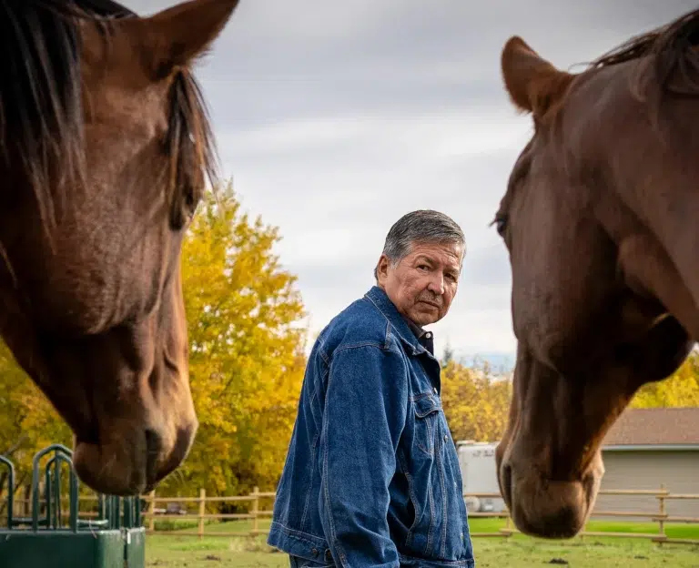 A person looks over their shoulder at two horses in the foreground during a brand video shoot.