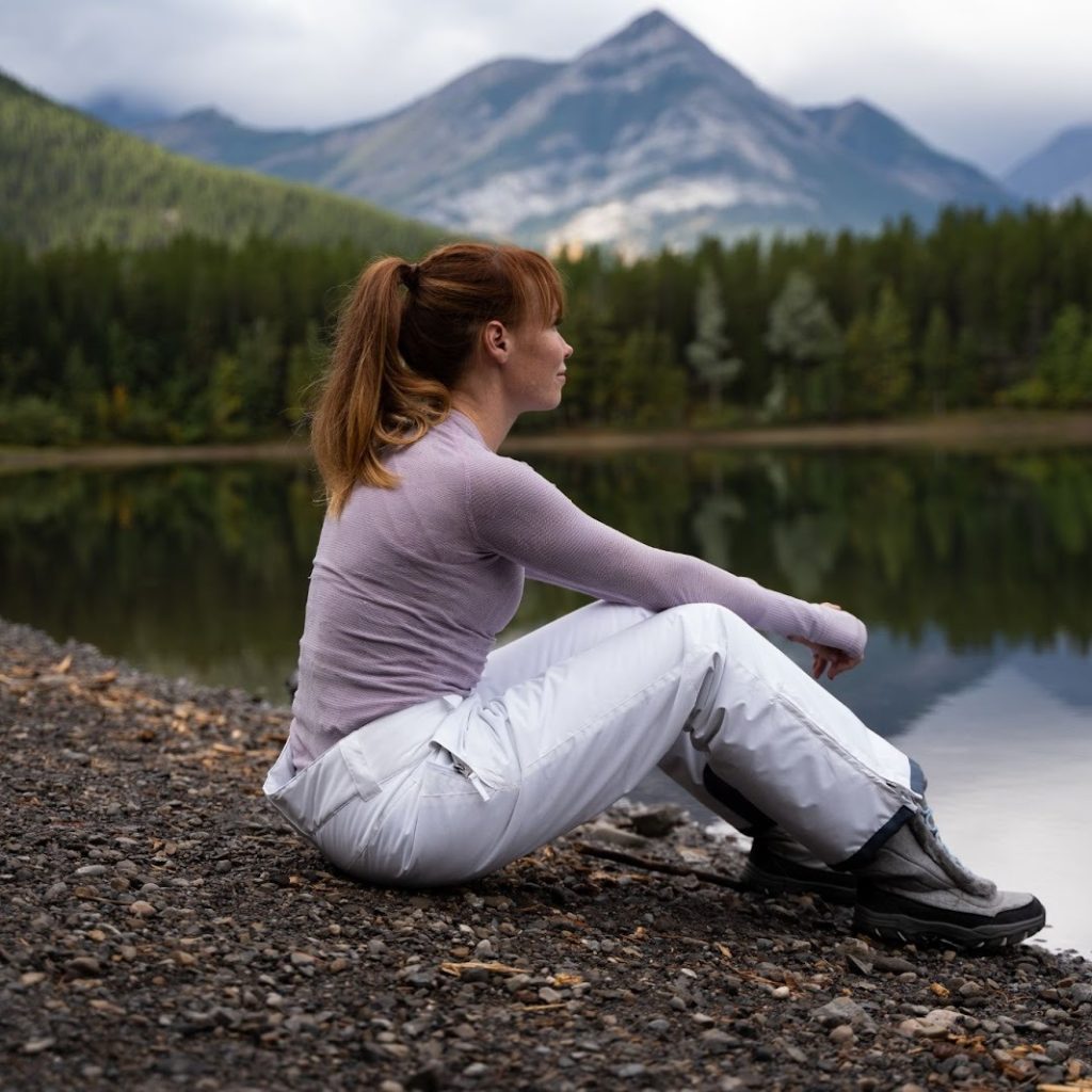 A person sits by a lake in Alberta during a brand video.