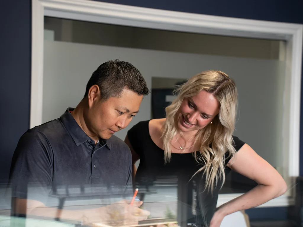 A behind the scenes shot of two coworkers looking at a document together.
