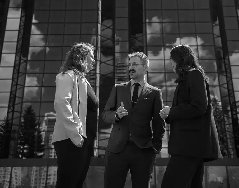 Three people stand in front of a building in downtown Calgary.