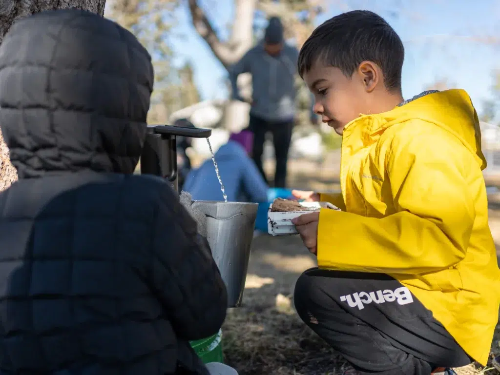 Children get water from a tap during a corporate video shoot for an environmental initiative.