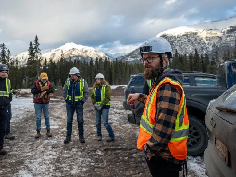A group of workers in PPE stands on a development site in Alberta for a corporate video.