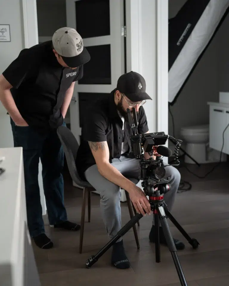 Two videographers look into a camera while recording a brand video.