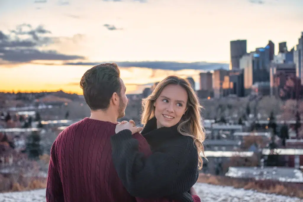 Two people pose on a hillside in Calgary at sunset during a video shoot.