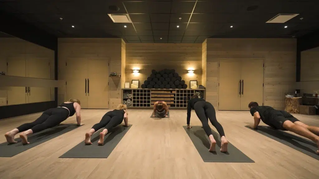 Four people hold a plank position during a yoga class for a corporate video.