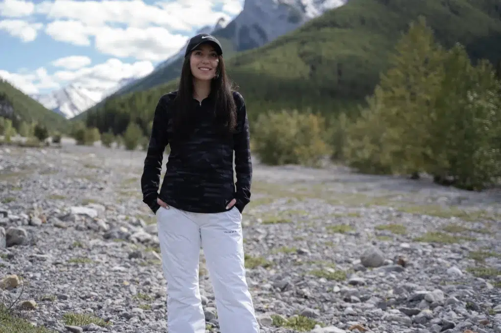 A person poses in front of the mountains outside on rocky terrain for a brand video.